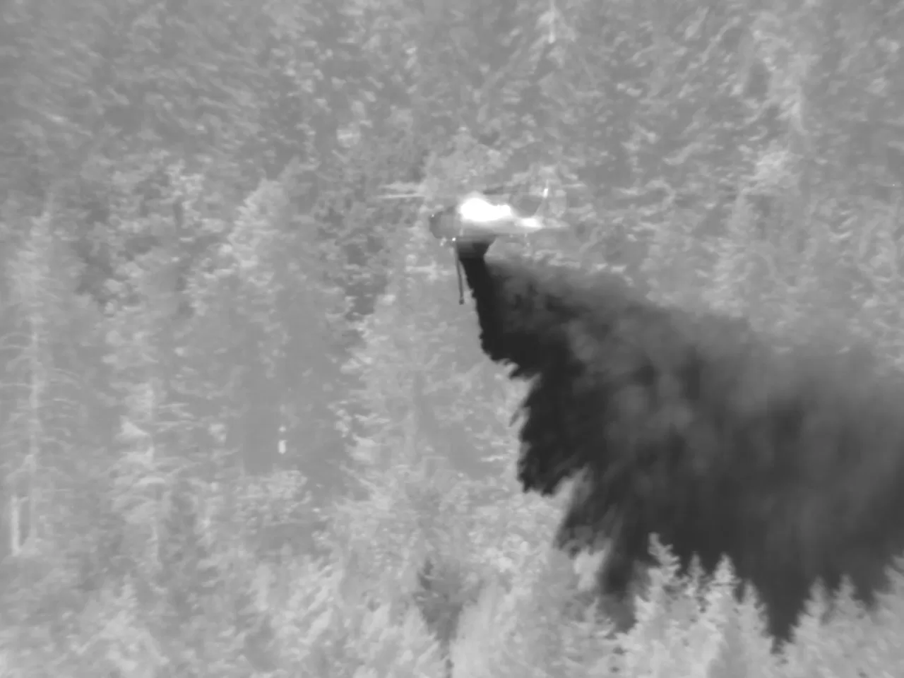 Helicopter dumping water on fire in infrared